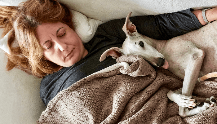 woman asleep in bed with her dog